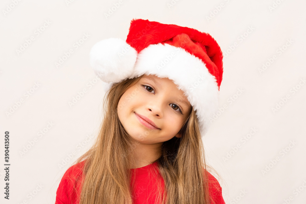 A beautiful little girl in a red t-shirt and a Christmas hat. A beautiful little girl in a red t-shirt and a Christmas hat.