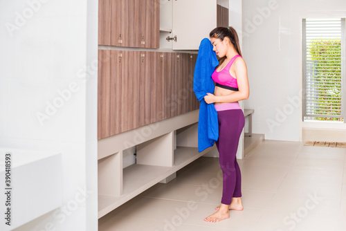 Tired asian woman having rest after workout. in locker room of sports center and row of wood locker in the room.