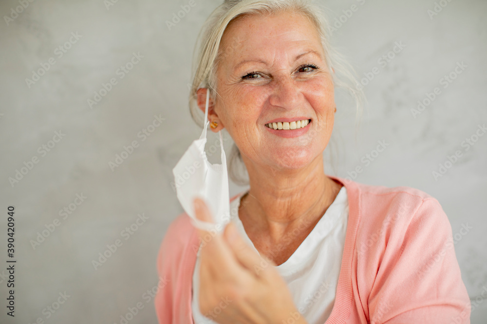 Portrait of senior woman taking off protective medical mask for protection from virus Portrait of senior woman taking off protective medical mask for protection from virus