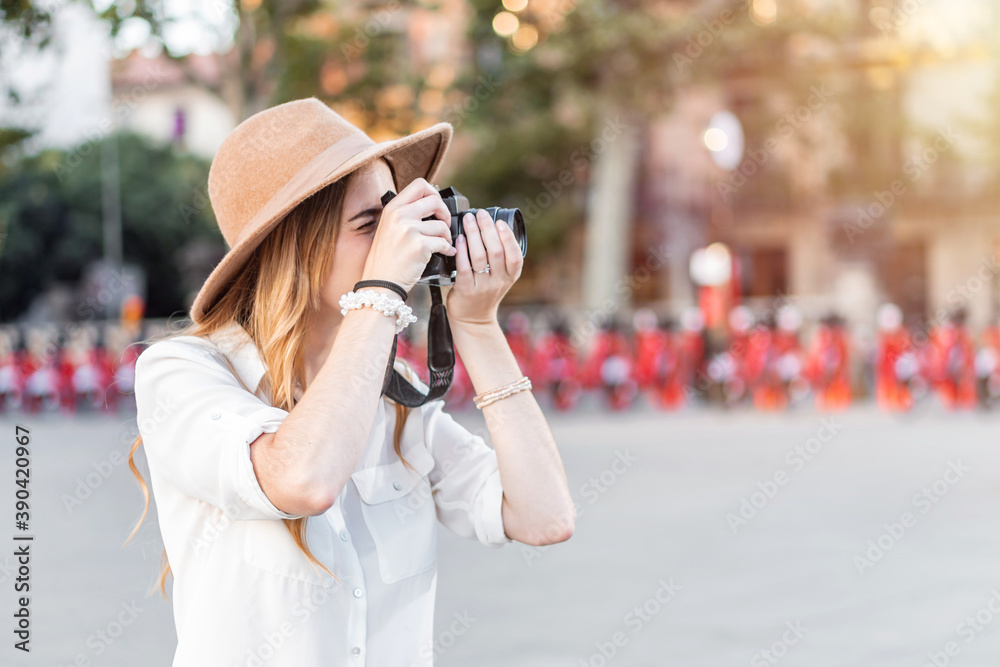 Portrait of a woman photographer using a vintage film camera and lens to take pictures outdoors. Female traveler taking a picture in the street
