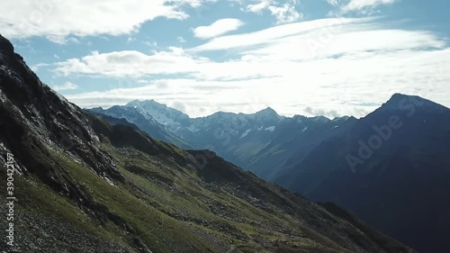 A panoramic drone shot of slopes in the Hohe Tauern region in Austria. The slopes are partially covered with snow. Upper parts steep and sharp. Early spring in the Alps. Serenity and calmness
 photo