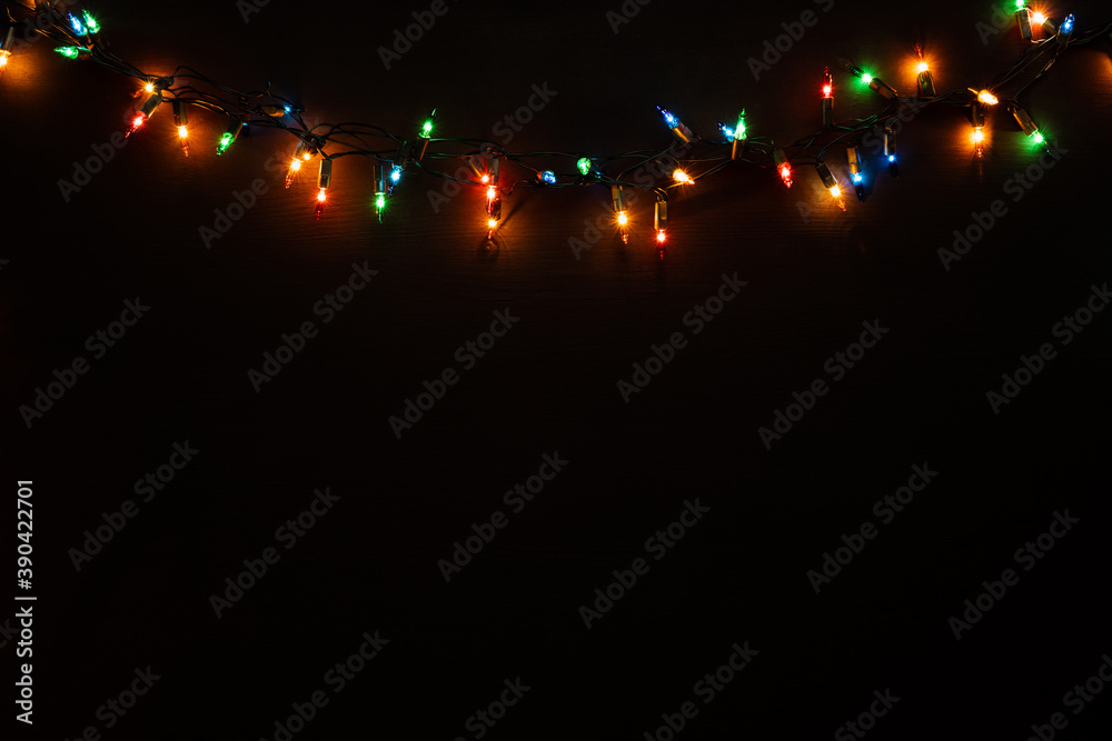 Black wooden background with christmas lights on the rustic wooden background. Flat lay. Selective focus. 