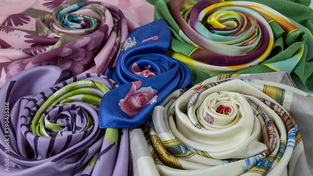 Texture, background  of  beautiful multi colored colored silk fabrics rolled up in the shape of a rose. +
