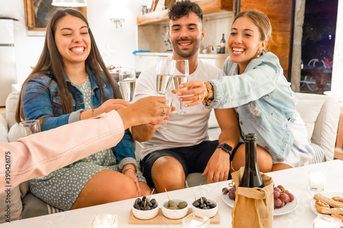Fotótapéta Young friends having fun toasting with champagne at home with aperitif snacks on
