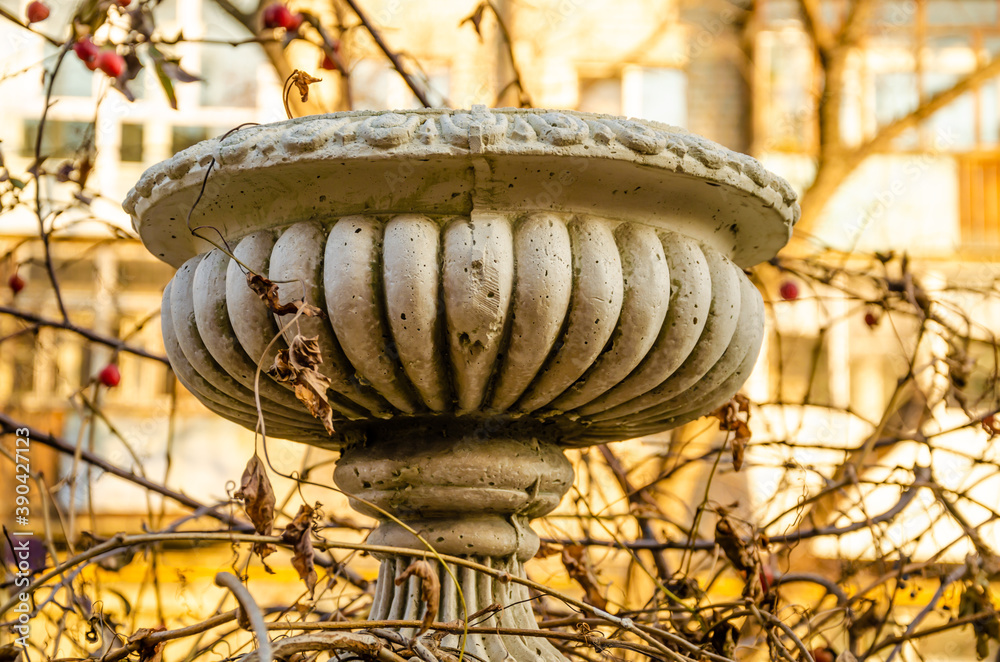 Stone round vase in autumn on the street.