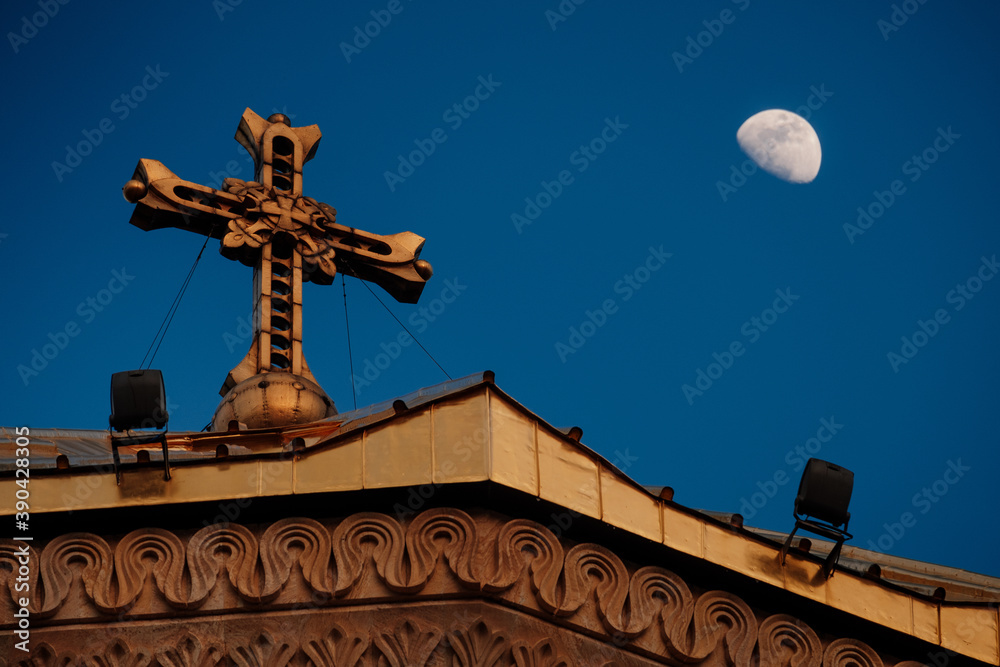 church cross on the roof against the background of a darkening sky and a growing moon