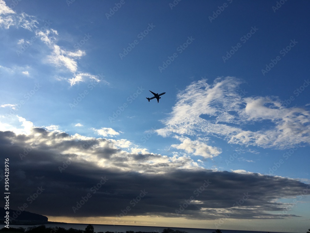 Flying airplane over blue cloudy sky 