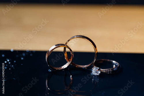 gold wedding rings for newlyweds on a wedding day on a black background with water drops. Jewelry