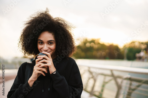 Cheerful beautiful sportswoman smiling and drinking coffee