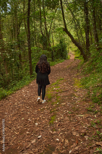 Mujer caminando por un camino de hojarasca en el bosque