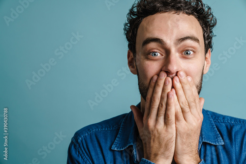 Caucasian excited guy posing and covering his mouth