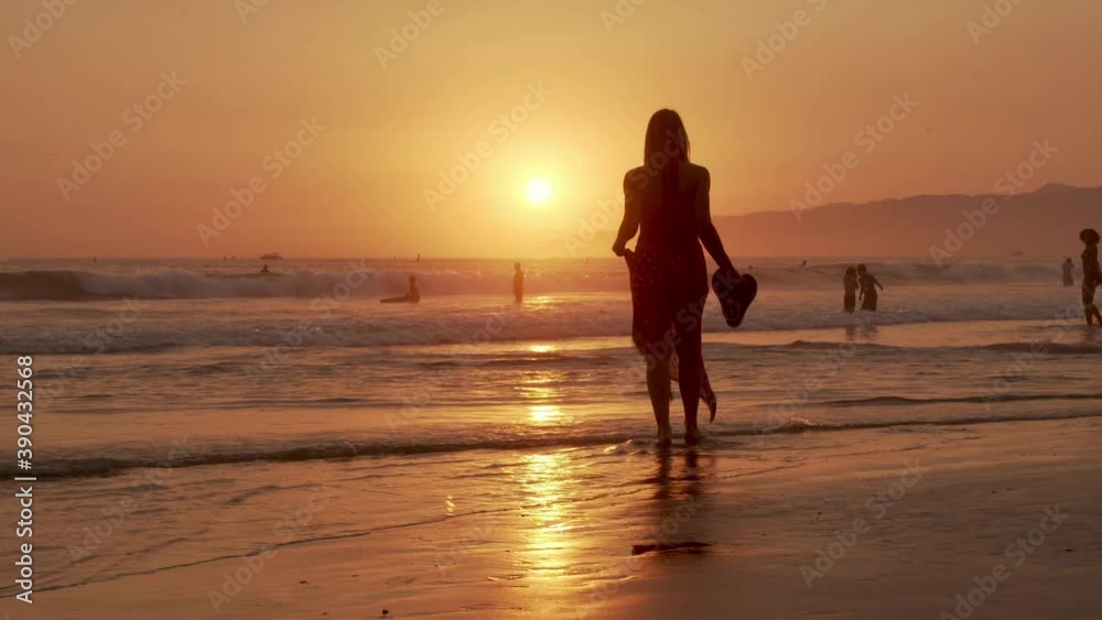 Silhouette of a Female in Summer Dress Walking on Beach at Sunset. Santa Monica, California USA Silhouette of a Female in Summer Dress Walking on Beach at Sunset. Santa Monica, California USA