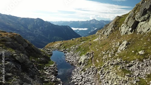 A panoramic shot of slopes in the Hohe Tauern region in Austria. The slopes are partially covered with snow. Upper parts steep and sharp. Early spring in the Alps. There is a small lake in the middle
