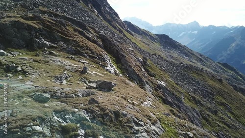 A panoramic shot of slopes in the Hohe Tauern region in Austria. The slopes are partially covered with snow. Upper parts steep and sharp. Early spring in the Alps. There is a small lake in the middle
 photo