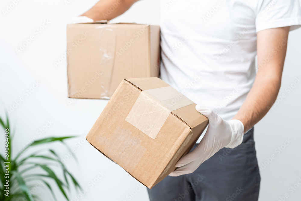 Delivery man holding cardboard boxes in medical rubber gloves and mask. copy space. Fast and free Delivery transport . Online shopping and Express delivery . Quarantine Delivery man holding cardboard boxes in medical rubber gloves and mask. copy space. Fast and free Delivery transport . Online shopping and Express delivery . Quarantine