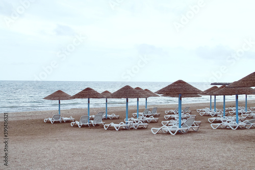 Tumbonas y sombrillas de paja en la playa Olimp en Rumania. Playa vacía un nublado y frío día de verano. © AngelLuis