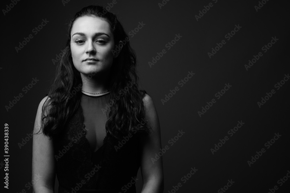 Studio shot of young beautiful woman against gray background