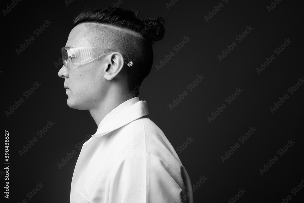 Young handsome multi ethnic man doctor against gray background