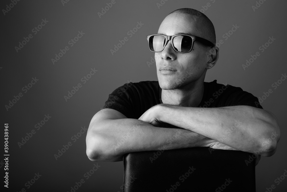 Handsome bald man wearing black shirt against gray background Handsome bald man wearing black shirt against gray background