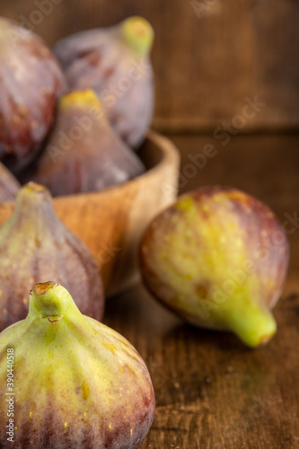 Top view of figs  with more background in wooden bowl  with selective focus  on wooden background  in vertical