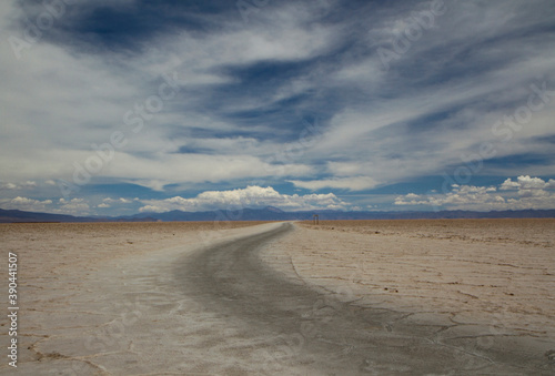 Empty dirt road along the desolated natural salt flat desert called Salinas Grandes, under a beautiful dramatic sky in Jujuy, Argentina. 