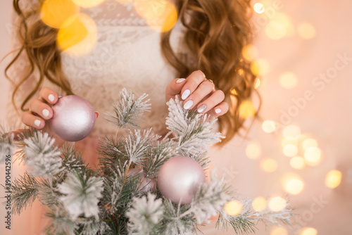 Woman's hand hanging silver Christmas ball on fir tree, holiday concept