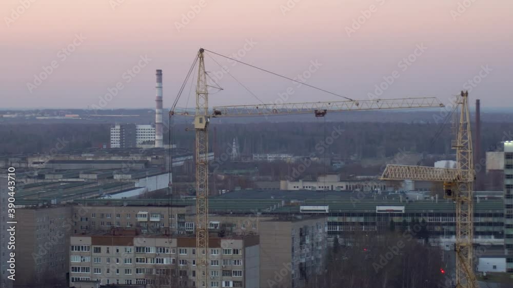 Two construction cranes are working at a construction site close-up. Two construction cranes are working at a construction site close-up.