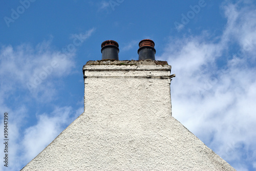 Detail of Gable with Two Chimney Pots on White Painted Building 