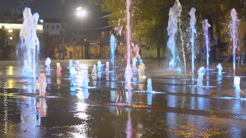 Multicolored fountains at night. Fountain illuminated with colored lights in the city park