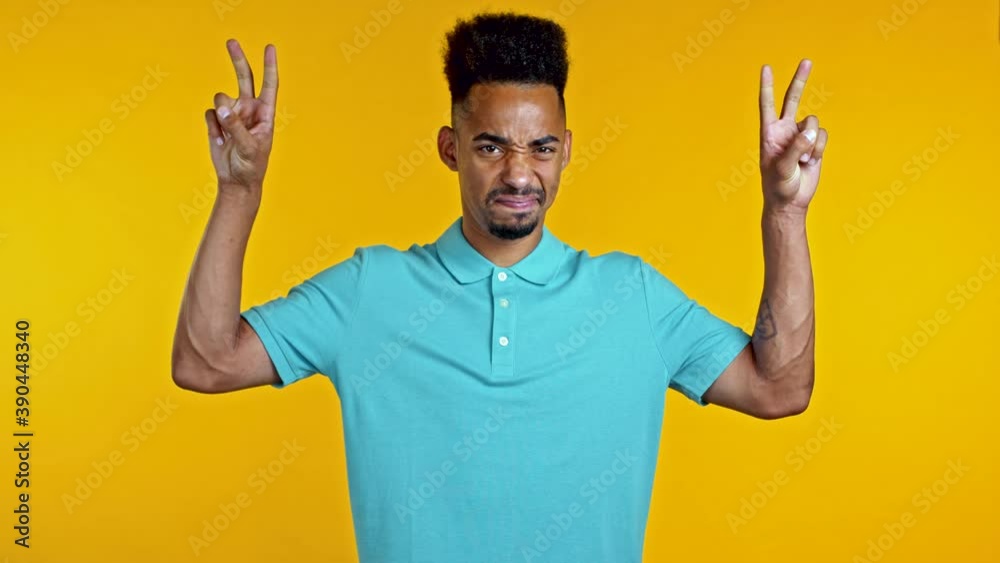 African man showing with hands and two fingers like quotes gesture, bend fingers isolated over yellow background. Very funny, irony and sarcasm concept. African man showing with hands and two fingers like quotes gesture, bend fingers isolated over yellow background. Very funny, irony and sarcasm concept.