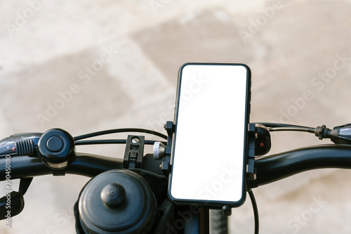 Close-up, mockup of a smartphone on the handlebars of a bicycle. Against the background of concrete and asphalt.