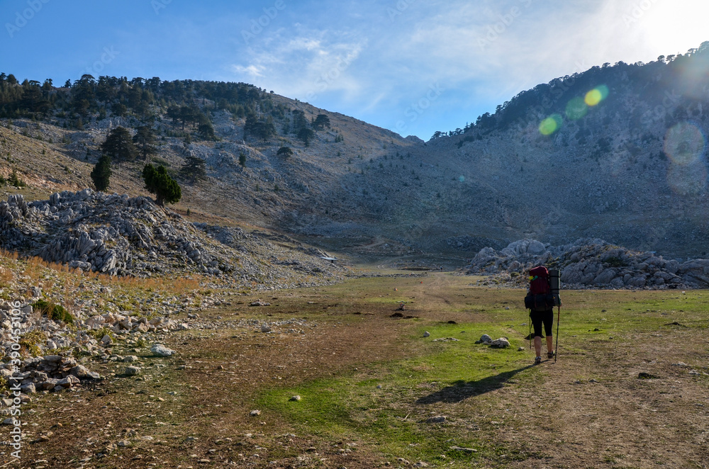 Girl hiker with backpack on a rocky hill in a mountain valley walk the Lycian way hiking trail at sunset