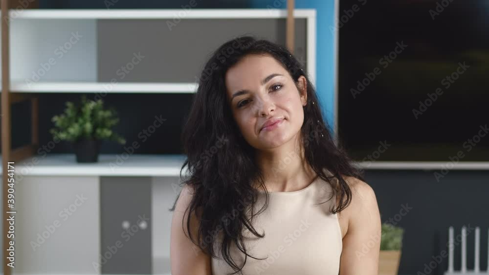 Smiling young woman brunette looking at camera at home office. Happy millennial female with pretty face posing indoors in apartment. Smiling young woman brunette looking at camera at home office. Happy millennial female with pretty face posing indoors in apartment.