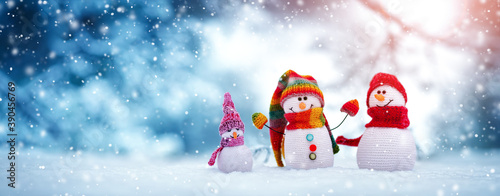 Little knitted snowmen on soft snow on blue background photo