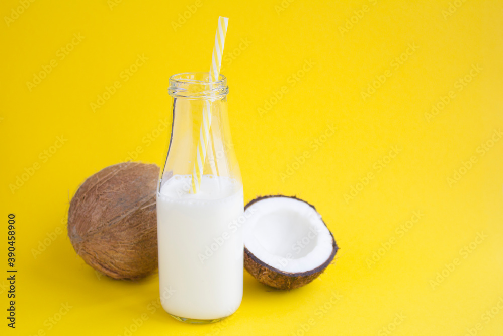 Coconut milk in the glass bottle on the yellow background with copy space Coconut milk in the glass bottle on the yellow background with copy space