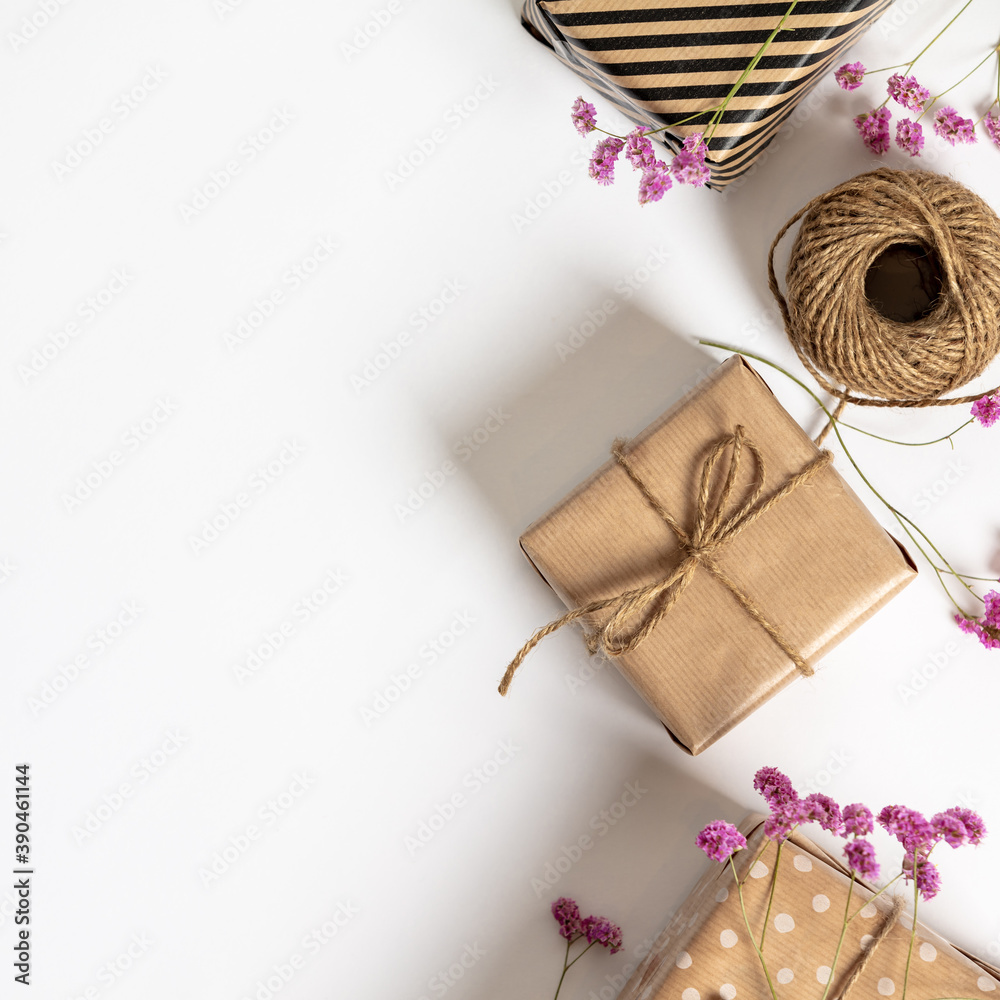 Gift box wrapped in kraft paper, notebook and pink flowers on white background. Flat lay styling. Gift box wrapped in kraft paper, notebook and pink flowers on white background. Flat lay styling.