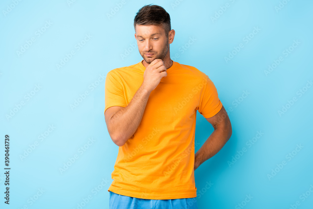thoughtful man in yellow t-shirt looking down on blue thoughtful man in yellow t-shirt looking down on blue