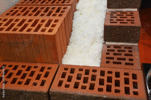 Fotografija A close-up of cross-section of an unfinished energy efficient, thermal insulated house wall built from porous ceramic blocks, polystyrene, and exterior alleviation exposed bricks
