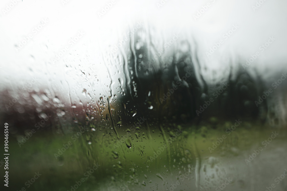 Obraz premium Shallow depth of field (selective focus) image with water pouring down outside a car window during a rainy day.
