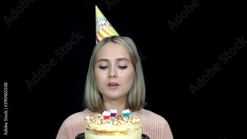 Woman in a birthday cap blows out the candles on the cakebirthday photo