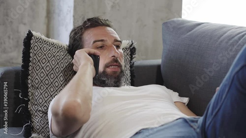 A relaxed man using mobile phone on the sofa at home 