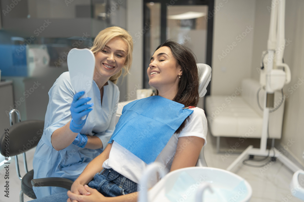 Obraz premium Female dentist in dental clinic providing examination and treatment of oral cavity for female patient.