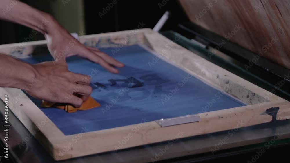 Man preparing silkscreen by hand for used to work printing t-shirts Man preparing silkscreen by hand for used to work printing t-shirts