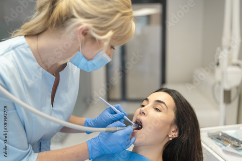 Female dentist in dental clinic providing examination and treatment of oral cavity for female patient.