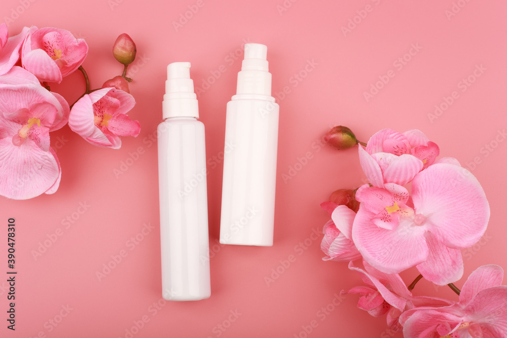 Flat lay with two unbranded creams in white bottles on pink background with flowers Flat lay with two unbranded creams in white bottles on pink background with flowers