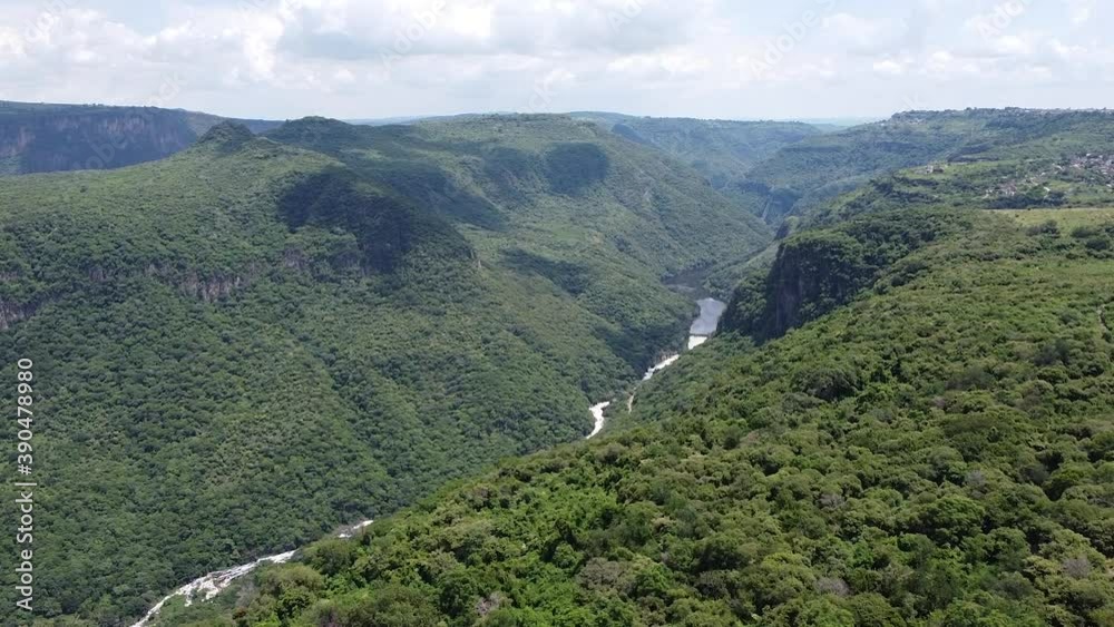 Vista aérea de una barranca verde de árboles y un río en el fondo