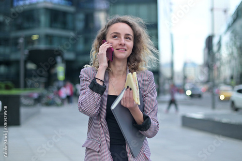 Young woman talking on the phone on the go and eating a sandwich