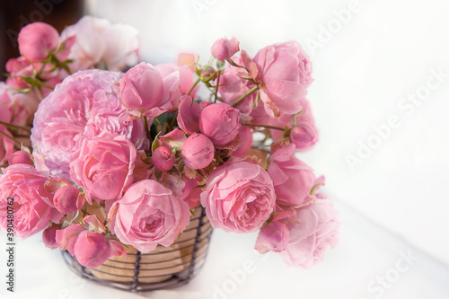 bouquet of pink English roses in a basket on a light table background. Close-up of rose buds  selective focus. Close up