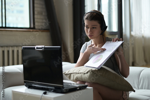 woman working remotely from home using laptop and headset