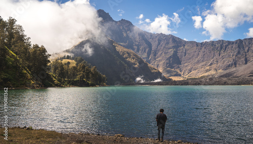 person from the back on the lake, mount Rinjani landscape with lake and mountains, volcano trekking in Indonesia